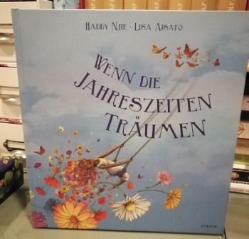 Buchcover vom Buch "Wenn die Jahreszeiten träumen". Hellblaub mit blumen und schaukelndem Kind