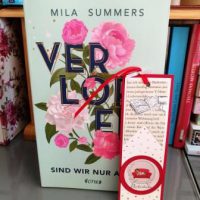 Türkis farbenes Cover mir dem Titel "Verloren sind wir nur allein" von Mila Summer. Das Wort "Verloren" ist gold umrandet und mit rosa farbenen Blumen umgebens
