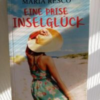 Buchcover im Sonnenlicht mit Frau auf dem Cover. Titel: Eine Prise Inselglück von Maria Resco